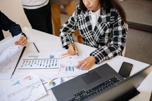 Free Businesswoman reviewing graphs and charts with colleagues, analyzing financial data in a modern office setting. Stock Photo