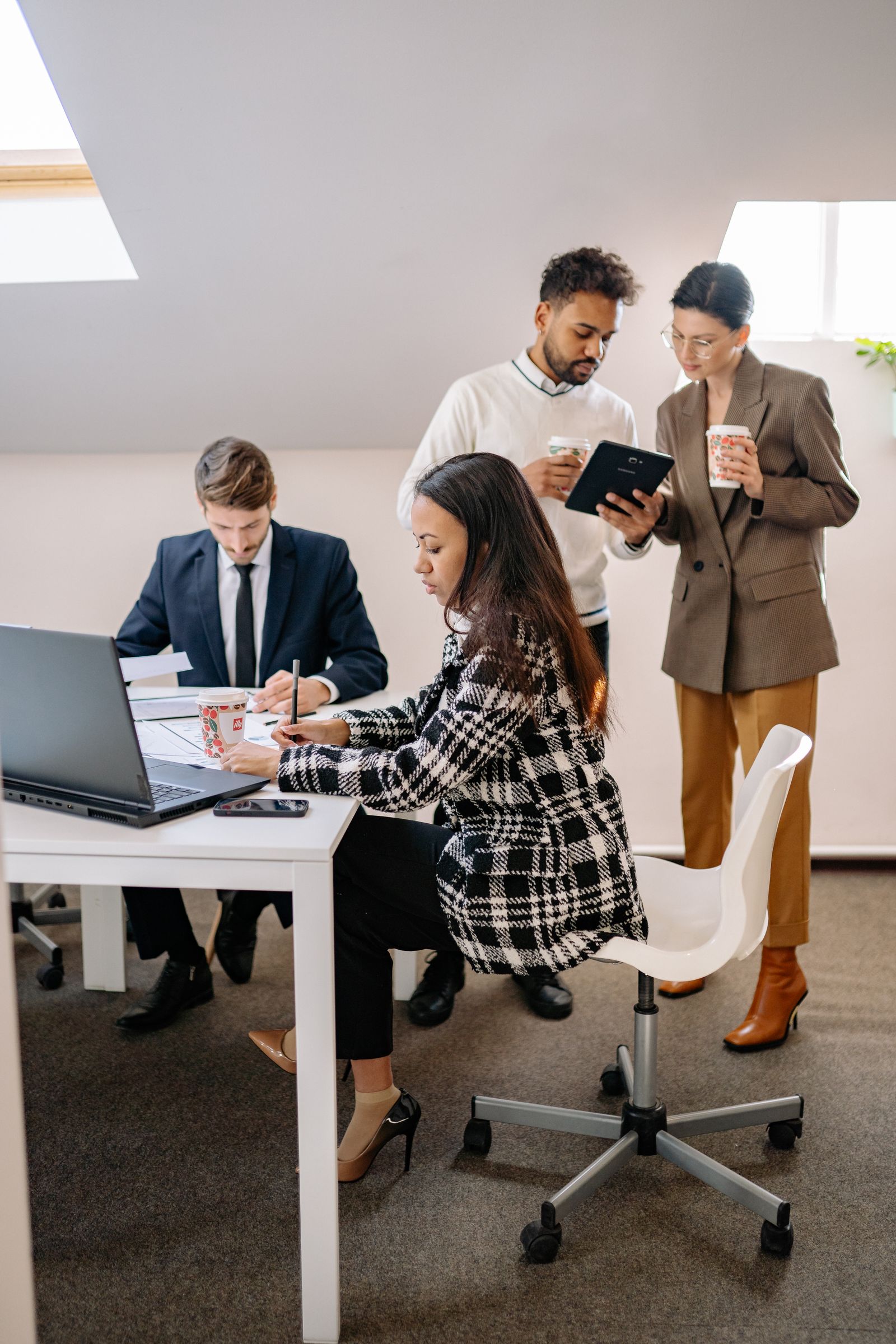 Diverse technology professionals collaborating around laptops and tablets in a modern office