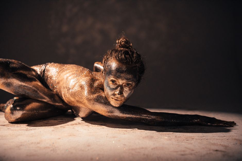 Artistic studio shot featuring a woman with glitter makeup, posing in a dynamic position.