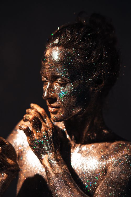 Free Model with glitter-covered skin showcasing artistic body art in a studio setting. Stock Photo