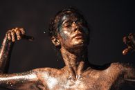 Artistic portrait of a woman covered in glitter posing against a dark background, showcasing creative expression.
