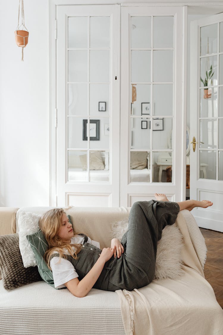 A Young Woman In Gray Jumper Lying On A Couch