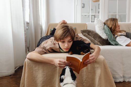 Teenage Boy Lying on Sofa While Reading a Book