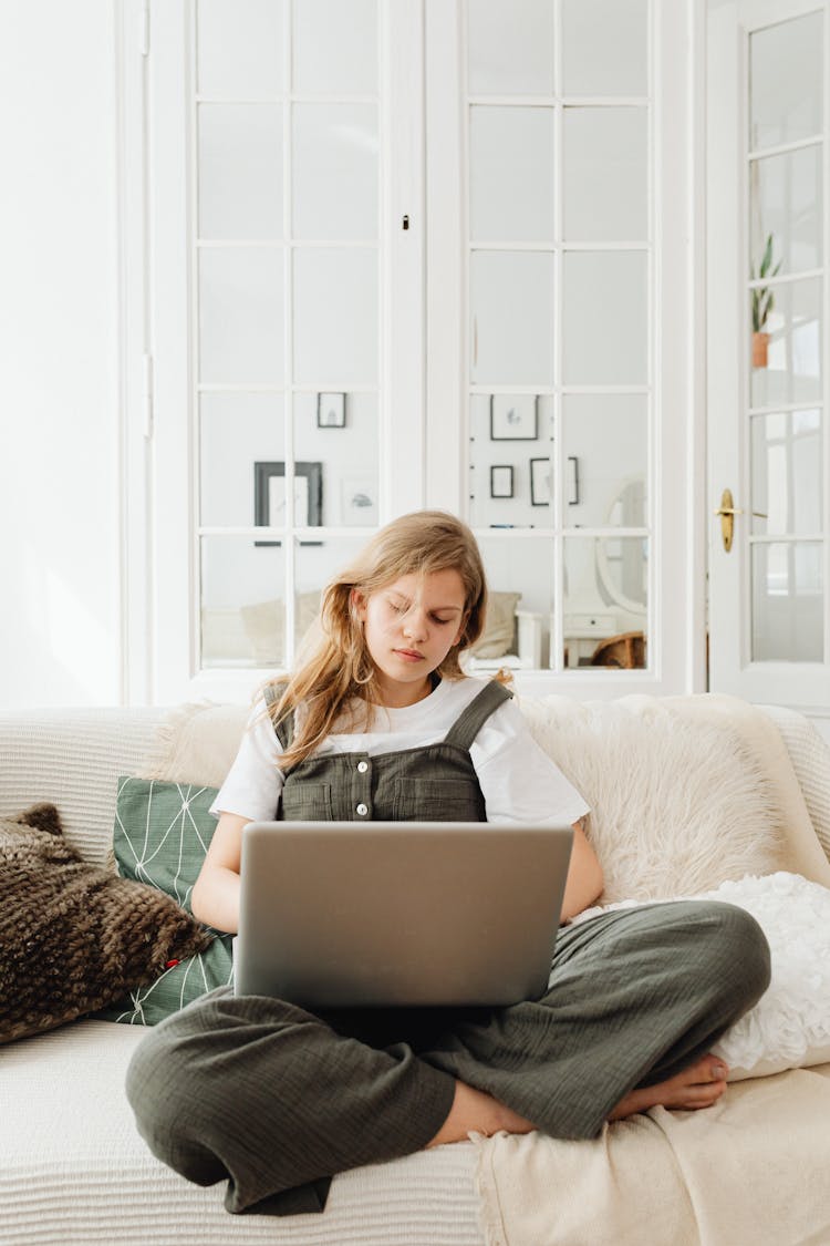 A Teenager Using A Laptop While Sitting On The Sofa