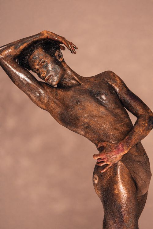 Free Elegant artistic portrait of a man covered in glitter with a graceful pose against a neutral backdrop. Stock Photo