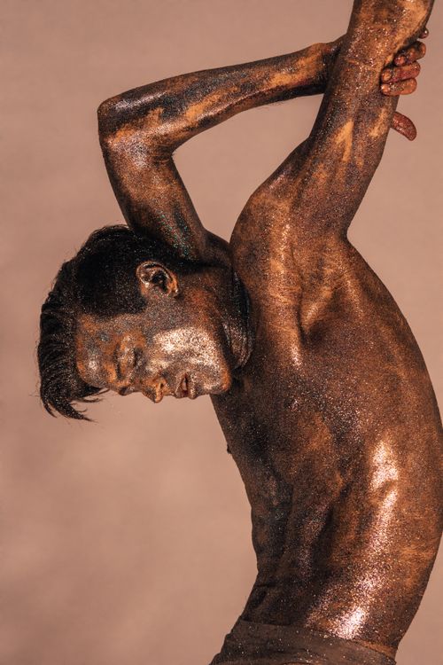 Free A sculptural male pose featuring glittering bronze body paint for a dramatic effect. Stock Photo