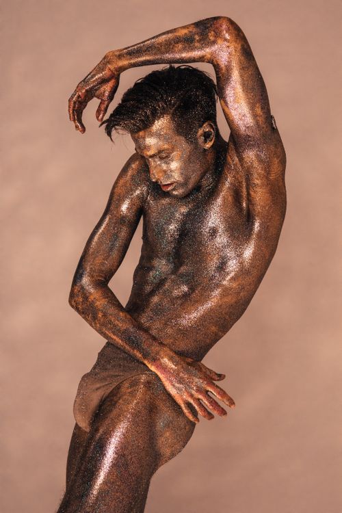 Free Shirtless male covered in glitter posing artfully against a neutral background. Stock Photo