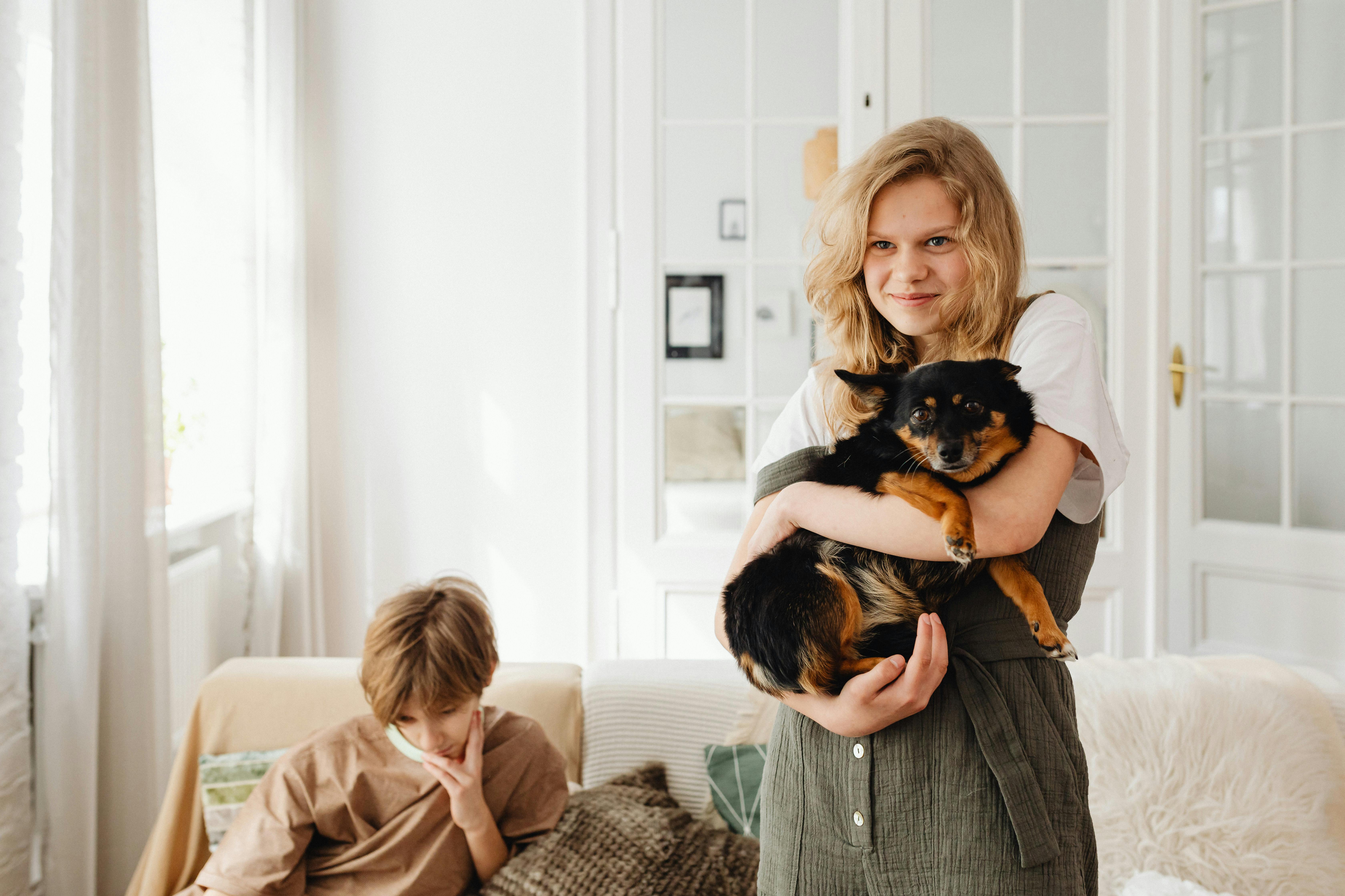 smiling girl carrying a black and brown short coat dog