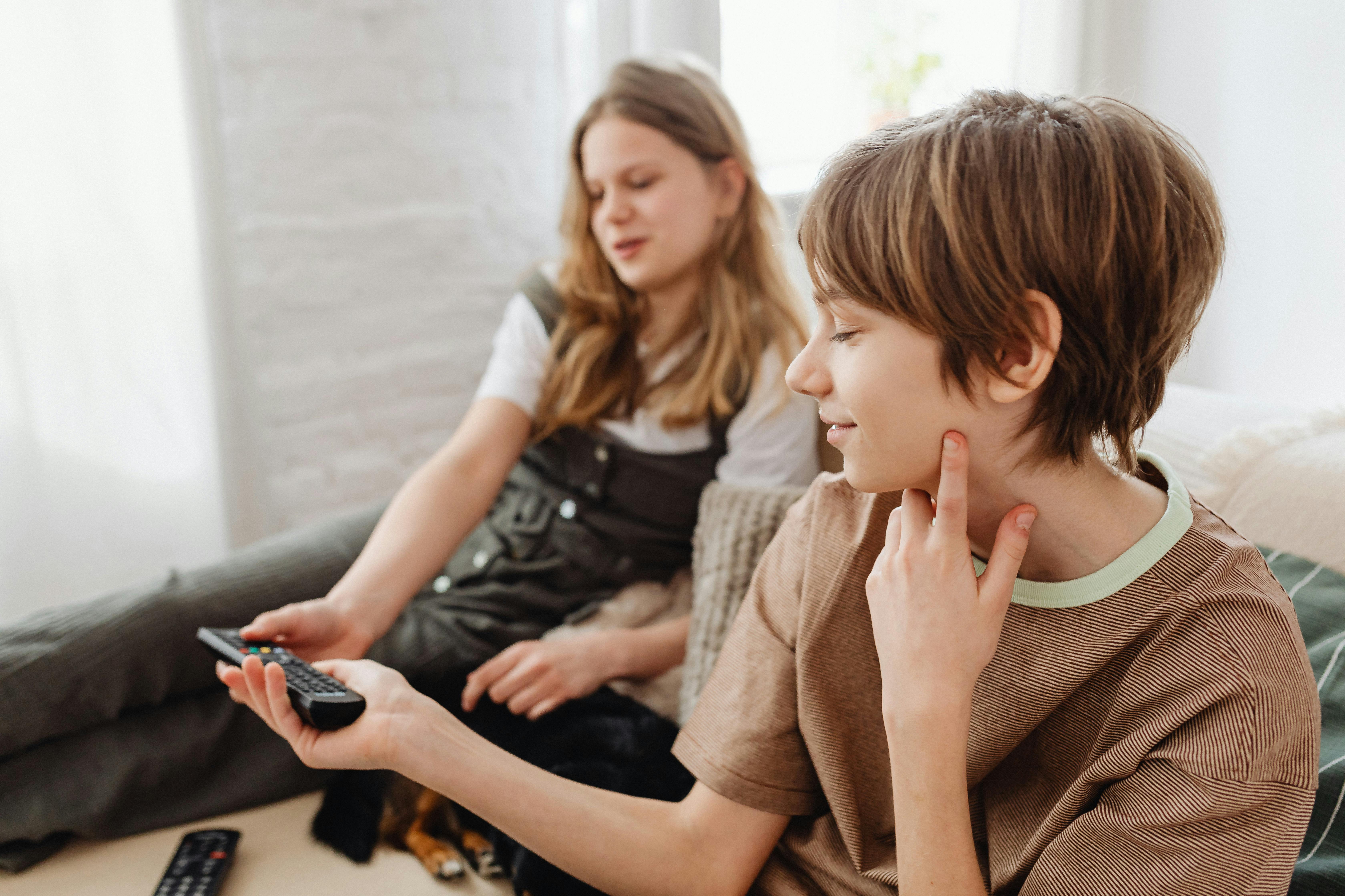 A Boy Handing the Remote Control to the Girl Sitting Next to Her