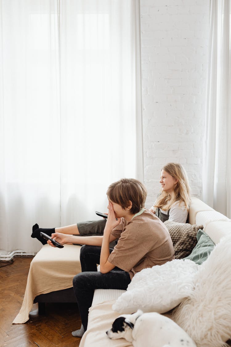 Siblings Watching While Sitting On The Sofa