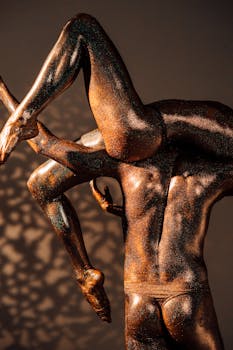 Unique artistic capture of two glitter-covered human figures posing creatively under warm lighting.