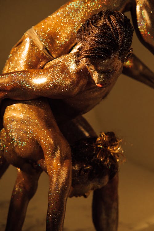 A Glittery Man and Woman Posing as Bronze Statue