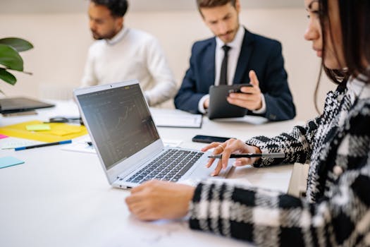 Professional team working on stock market analysis with laptops and tablets in modern office setting.