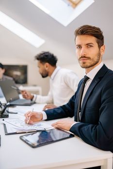 Confident businessman in formal attire attending a meeting in a modern office setting.