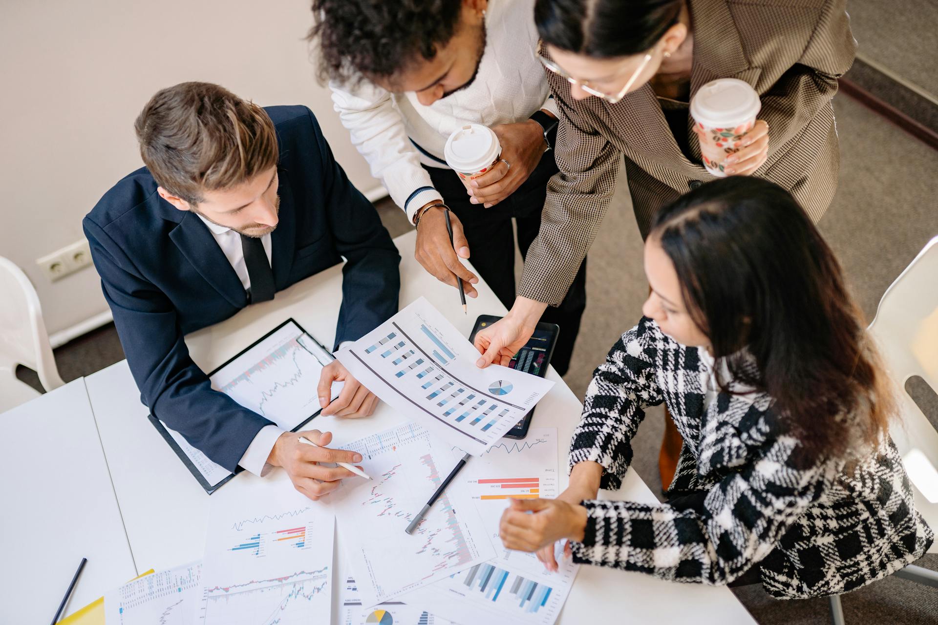 A diverse team in business attire collaborates over graphs and charts for a successful project.