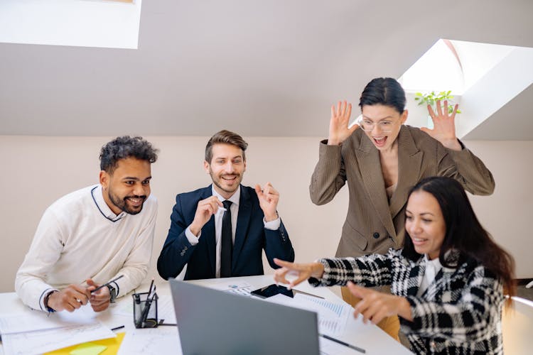 A Group Of Happy People Looking At A Laptop 