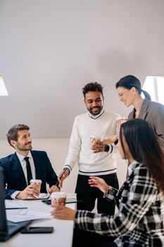 Diverse business team enjoying a coffee break indoors, fostering collaboration and teamwork.