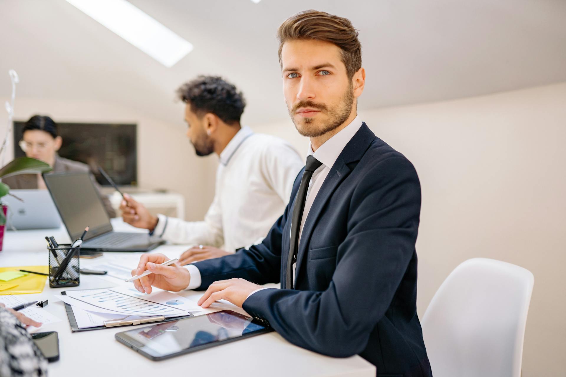 Confident businessman working with a team in a modern office, teamwork and collaboration vibe.