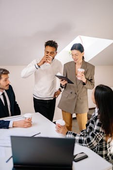 Colleagues in a modern office enjoying coffee during a collaborative meeting.