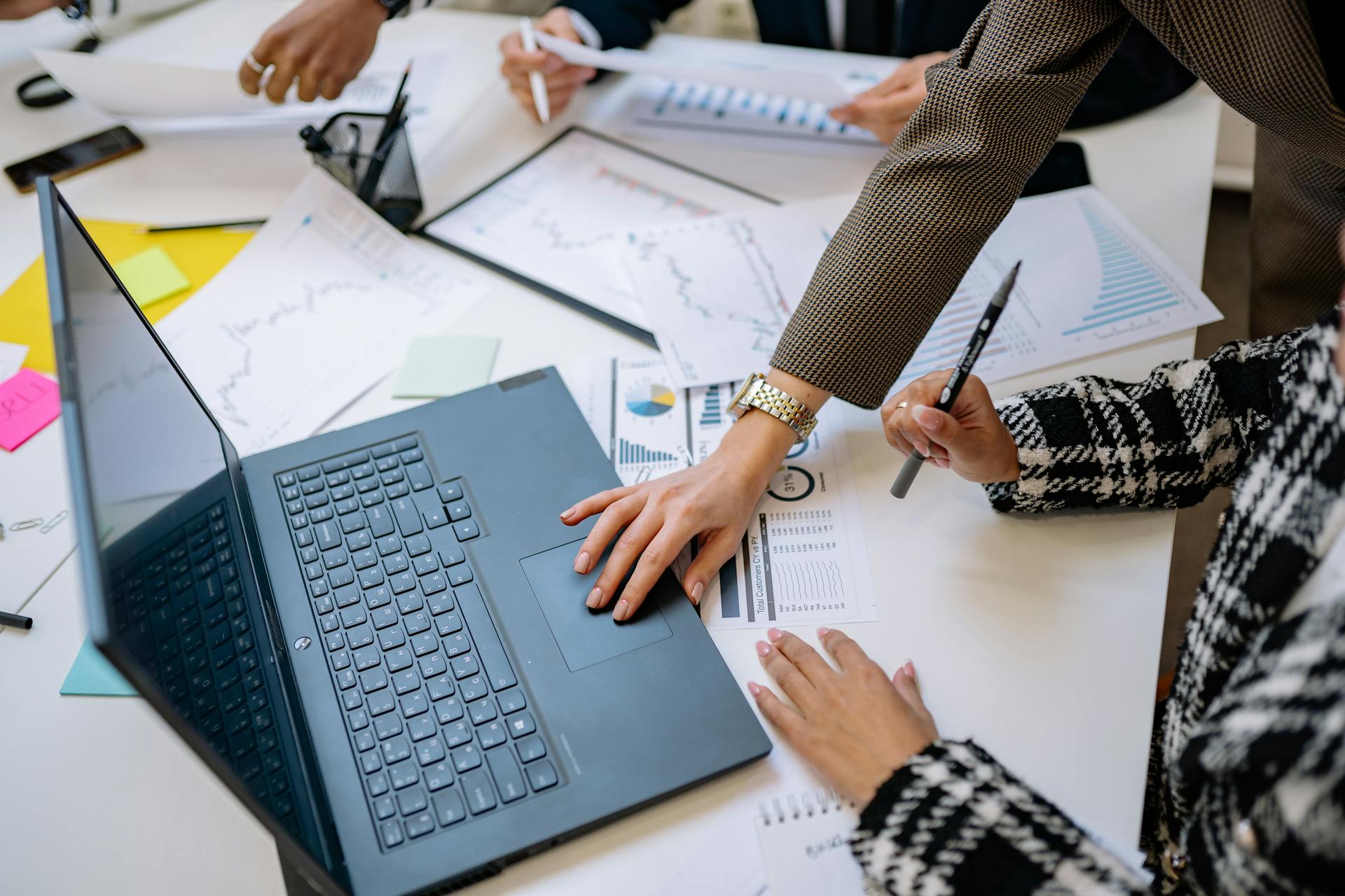 Business team analyzing data and charts during a meeting with a laptop on the table.