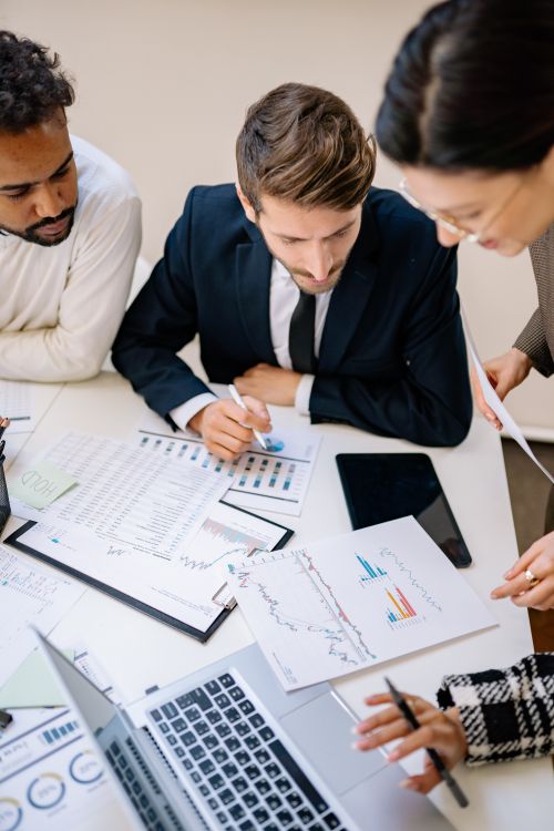 Free Business professionals collaborating over charts and laptops in an office. Stock Photo