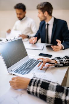 Professionals collaborating with technology to analyze stock market trends on a laptop.