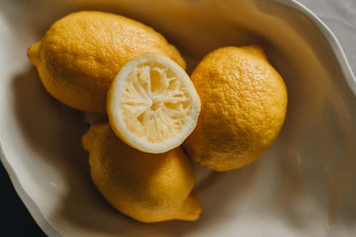 Top view of fresh ripe sour lemons placed on light ceramic plate in daylight