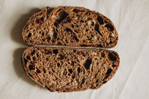 Free Top view slices of freshly baked black cranberry bread placed on crumpled tablecloth on table in light room in studio Stock Photo