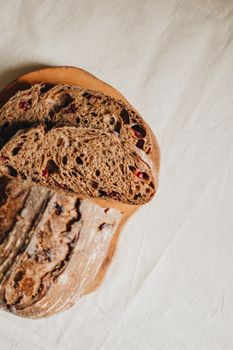 Top view slices of fresh tasty black cranberry bread served on wooden cutting board on white table in light room