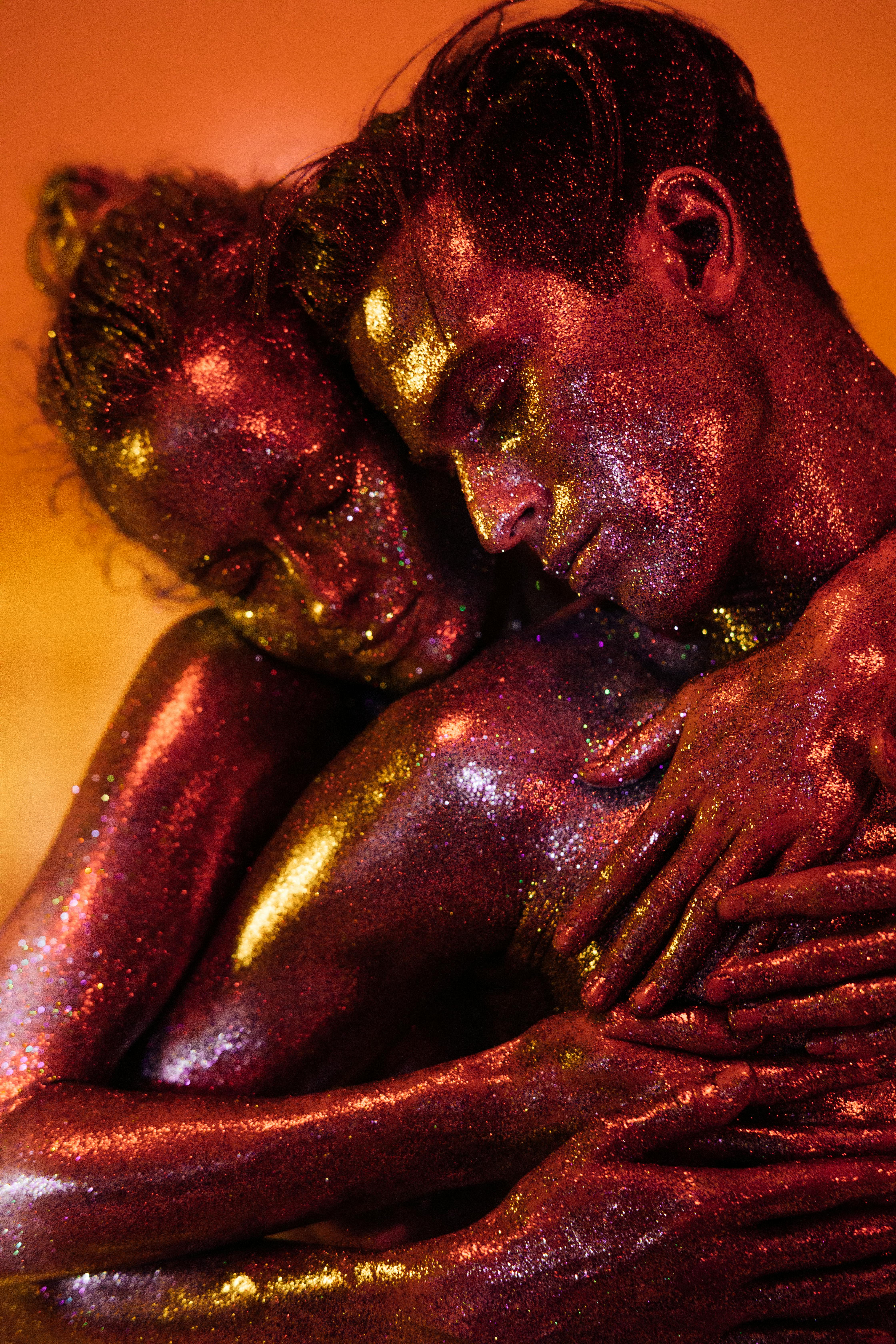 a man and a woman with glittery body paint hugging each other