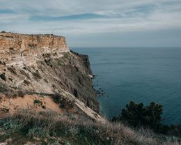 A grassy headland dropping to open ocean. Photo by Dmitriy Ganin on Pexels