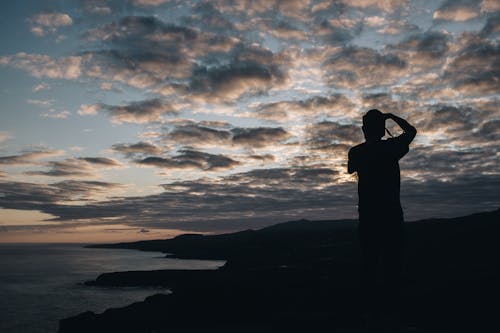 
A Silhouette of a Man under a Cloudy Sky