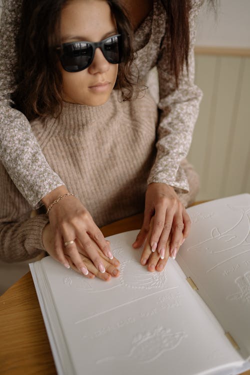 Free A Girl Using Both Hands to Read Braille Stock Photo
