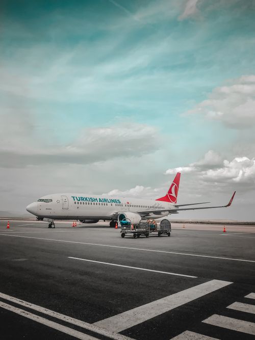 Free Turkish Airlines plane parked on airport tarmac with clear blue sky and clouds. Stock Photo