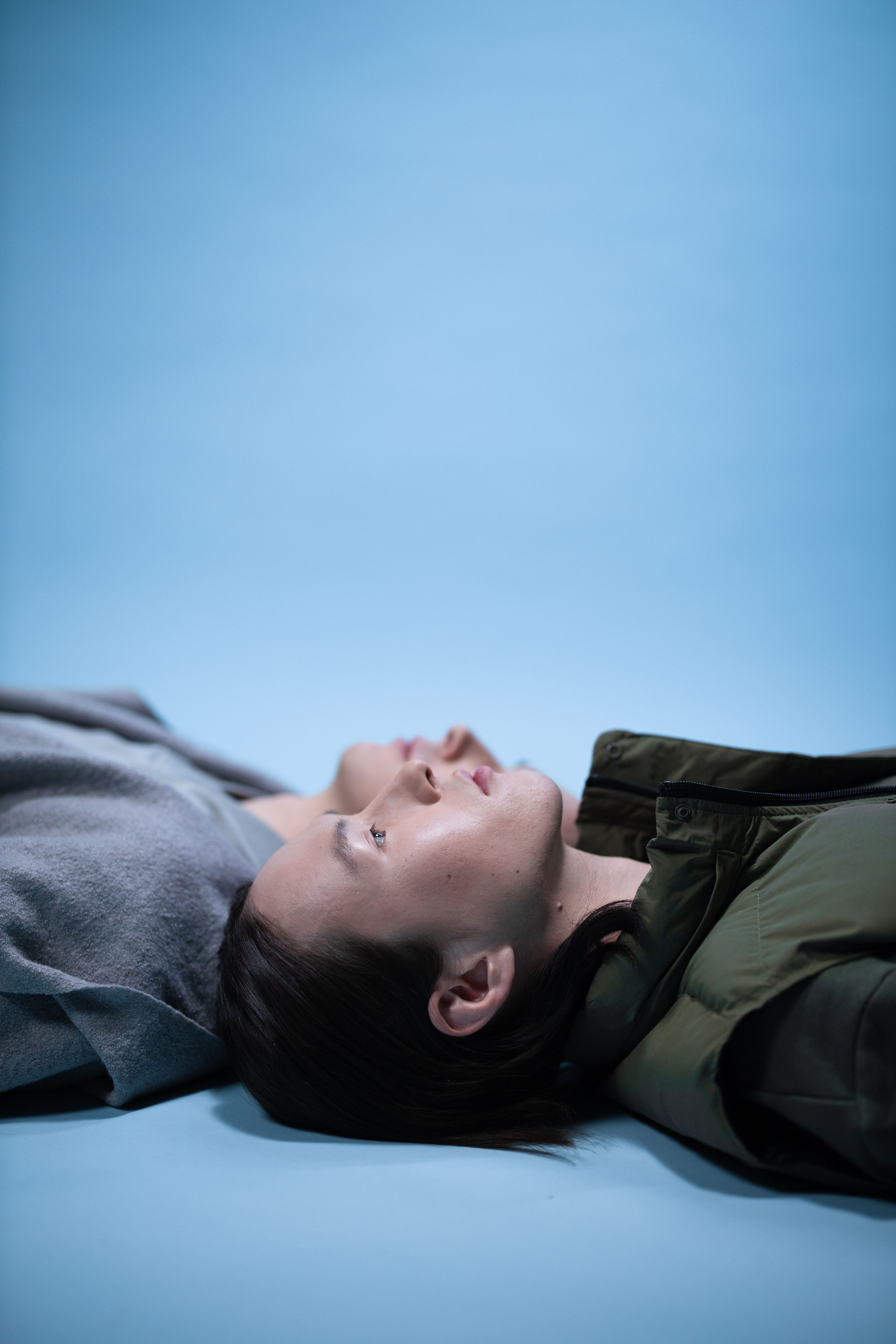 Two Asian men lying down on a blue surface, reflecting calmness and friendship.