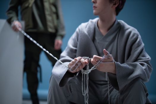 Contemplative scene with two people holding chains, artistic setting.