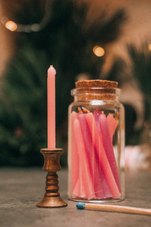 Candles placed in glass jar against blurred background in room