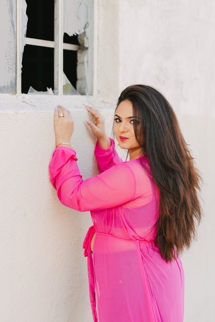 A Woman Posing Near A Broken Window