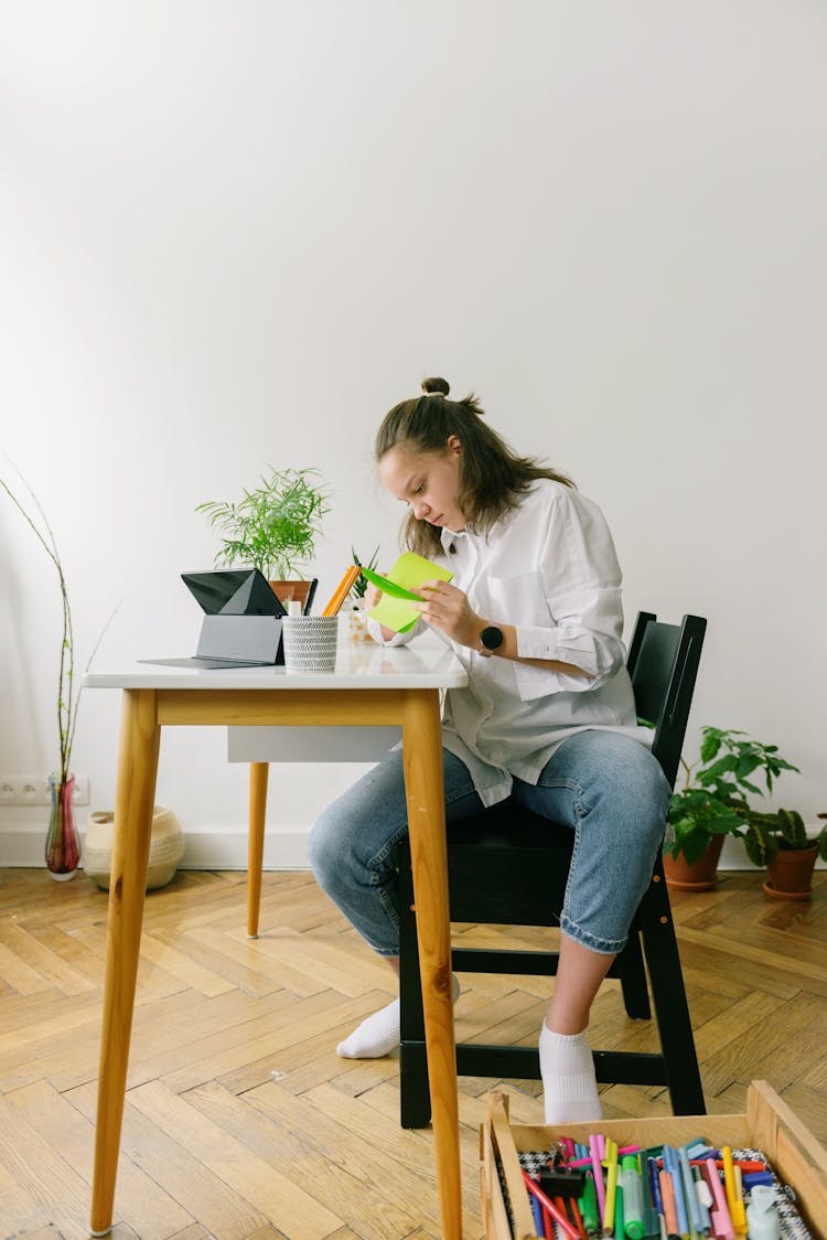 A Teenager Making A Papercraft Project At Home