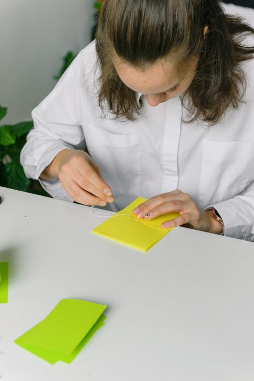 Free Woman in white shirt engaged in paper crafting at a desk indoors. Stock Photo