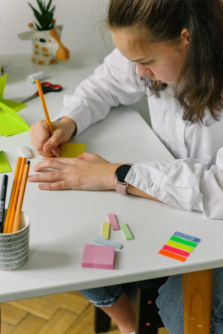 A Teenager Writing On A Paper