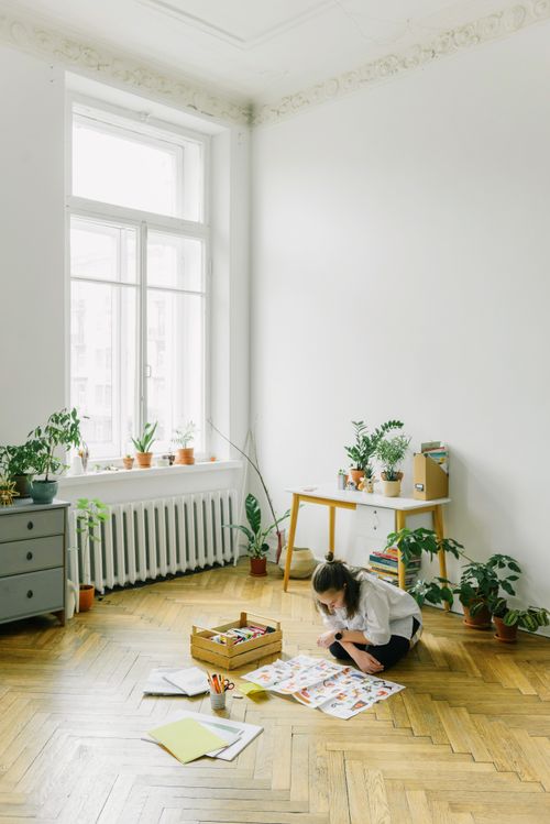 Free Teenage girl creating artwork at home surrounded by plants and natural light. Stock Photo