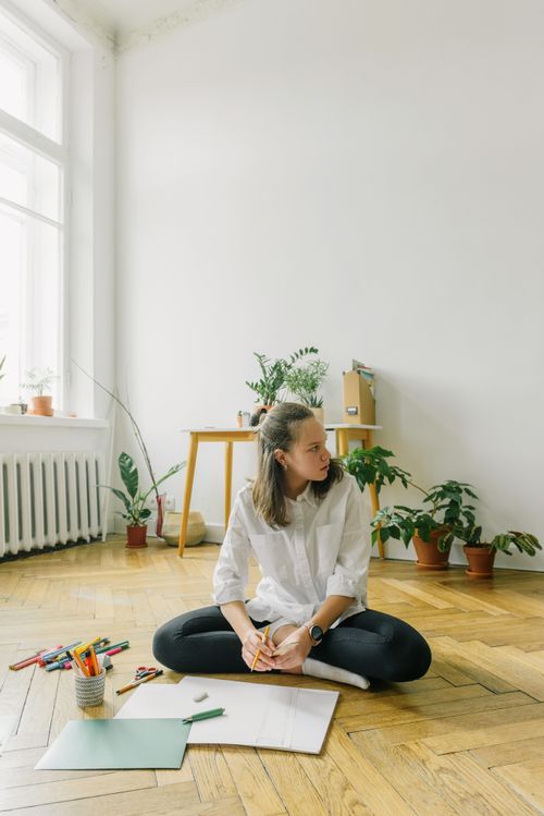 Free Young woman in a bright room working on an art project, surrounded by plants. Stock Photo