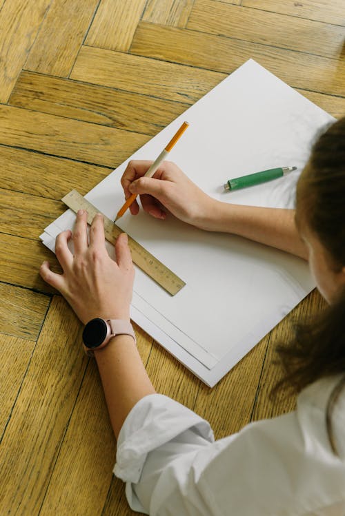 Free A Person Drawing a Line with a Ruler on Illustration Board Stock Photo