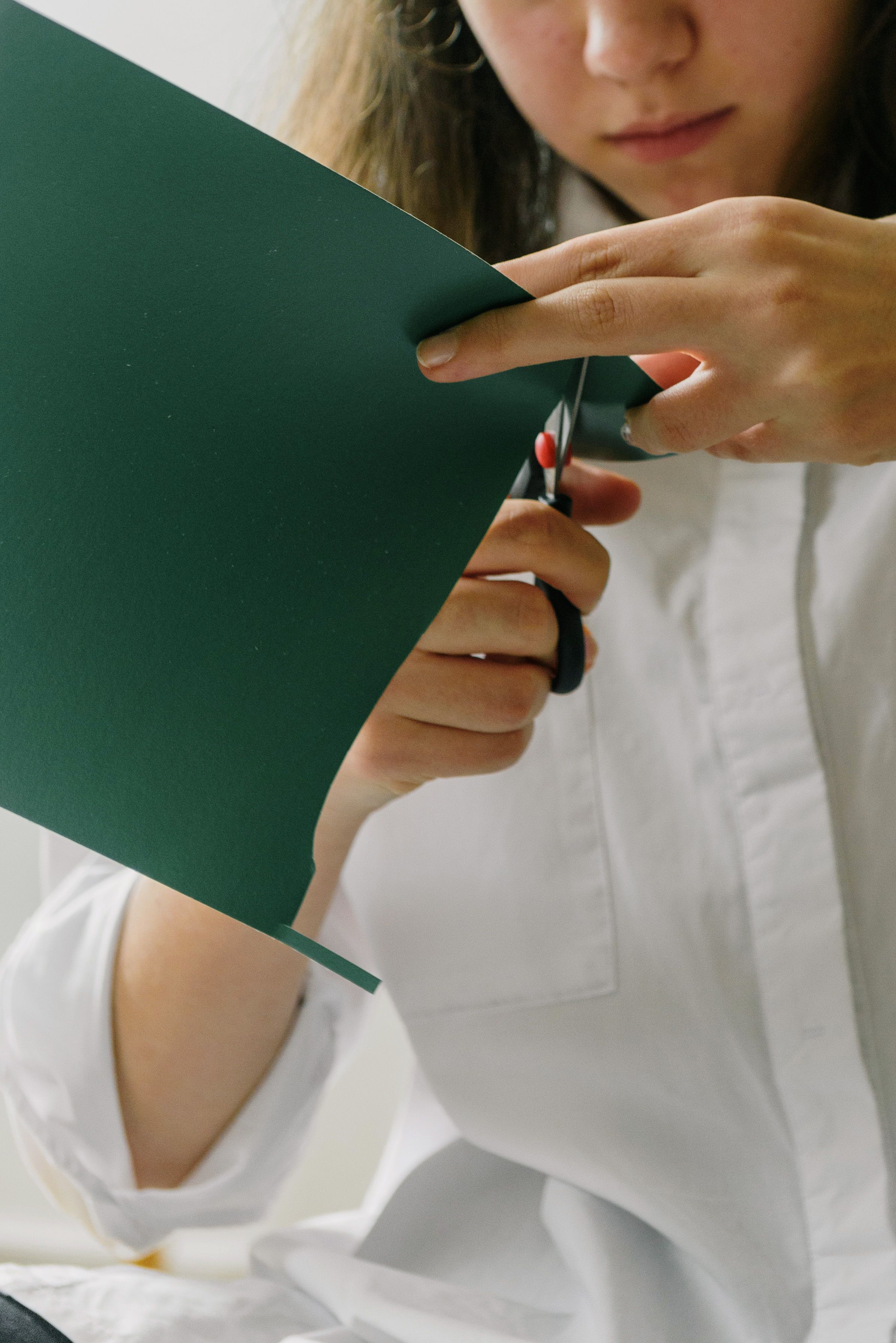 Crop young craftswoman cutting paper sheet · Free Stock Photo