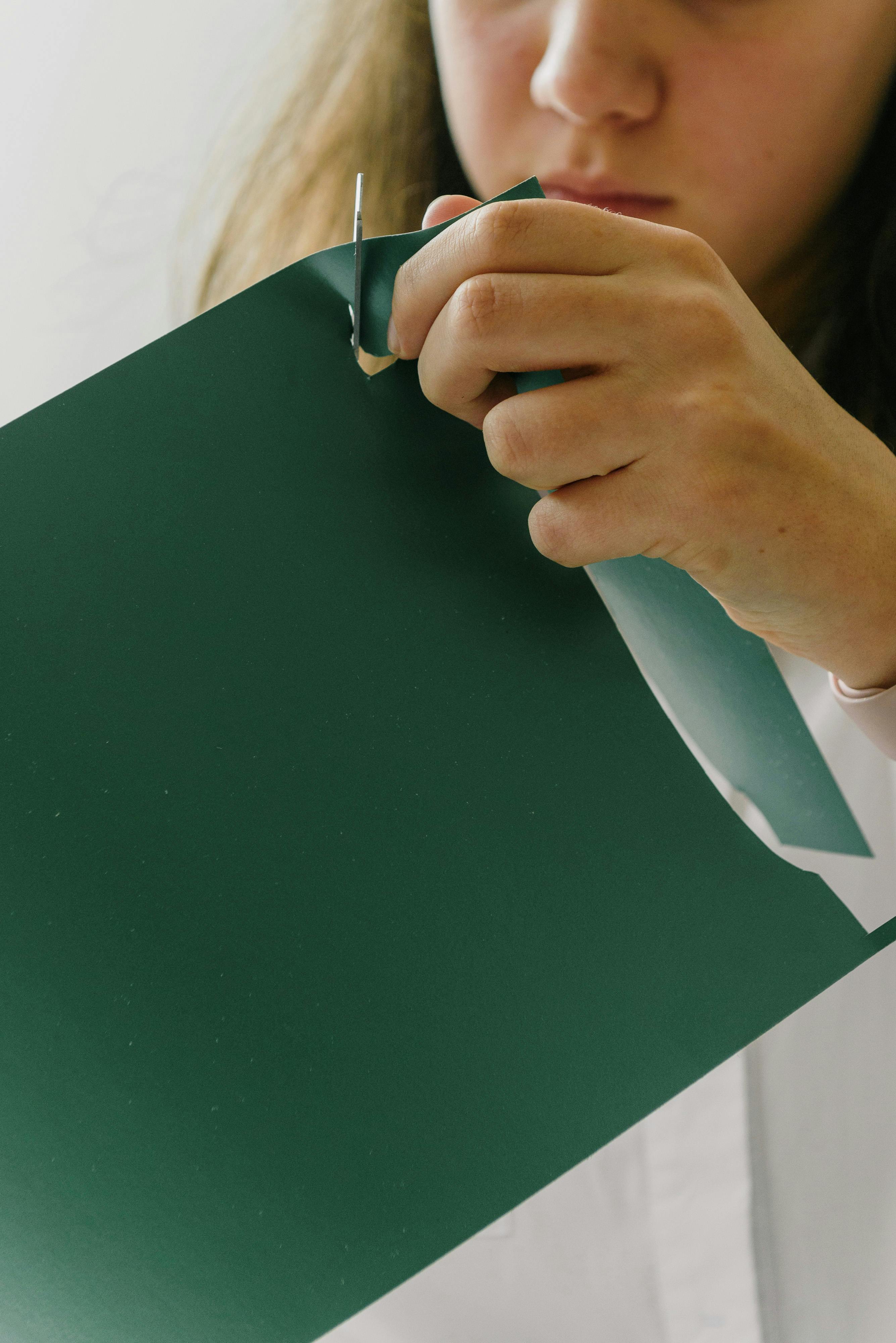 Close Up Of Hand Holding Scissors And Cutting Through Paper Stock