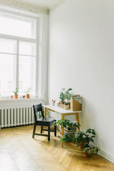 Bright minimalist home office with wooden floor, plants, and sunlight through window.