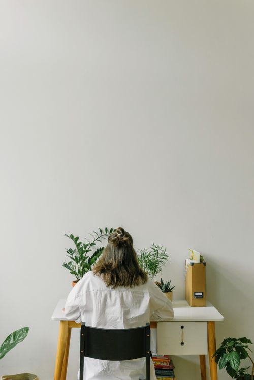 Free Female working from a minimalistic home office desk surrounded by plants. Stock Photo