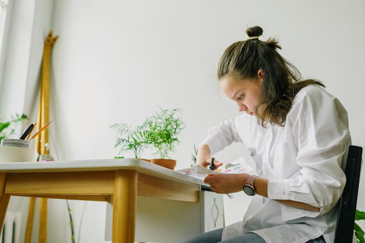 Woman In White Long Sleeve Shirt Cutting White Paper