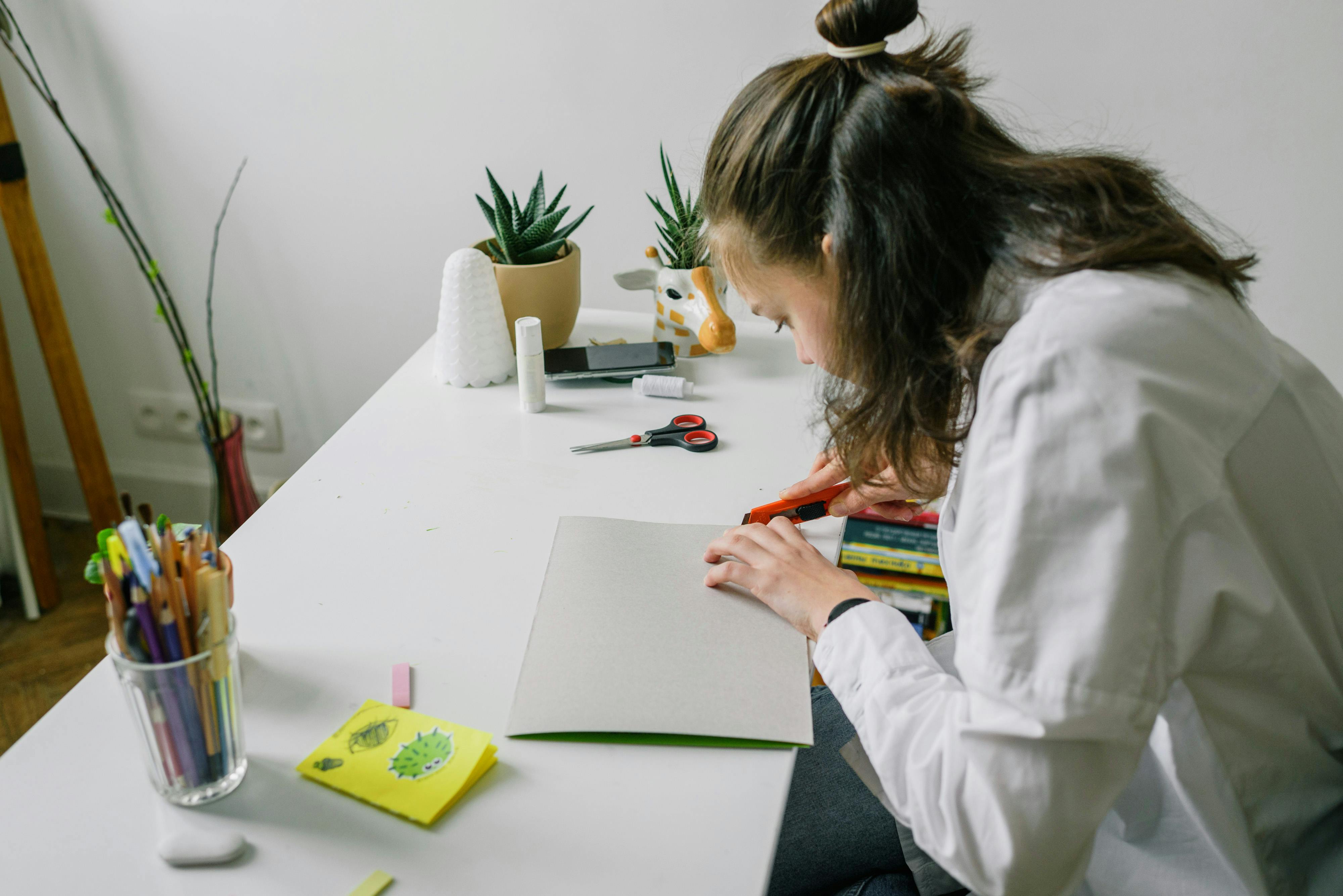 a girl in white long sleeve shirt doing an artwork